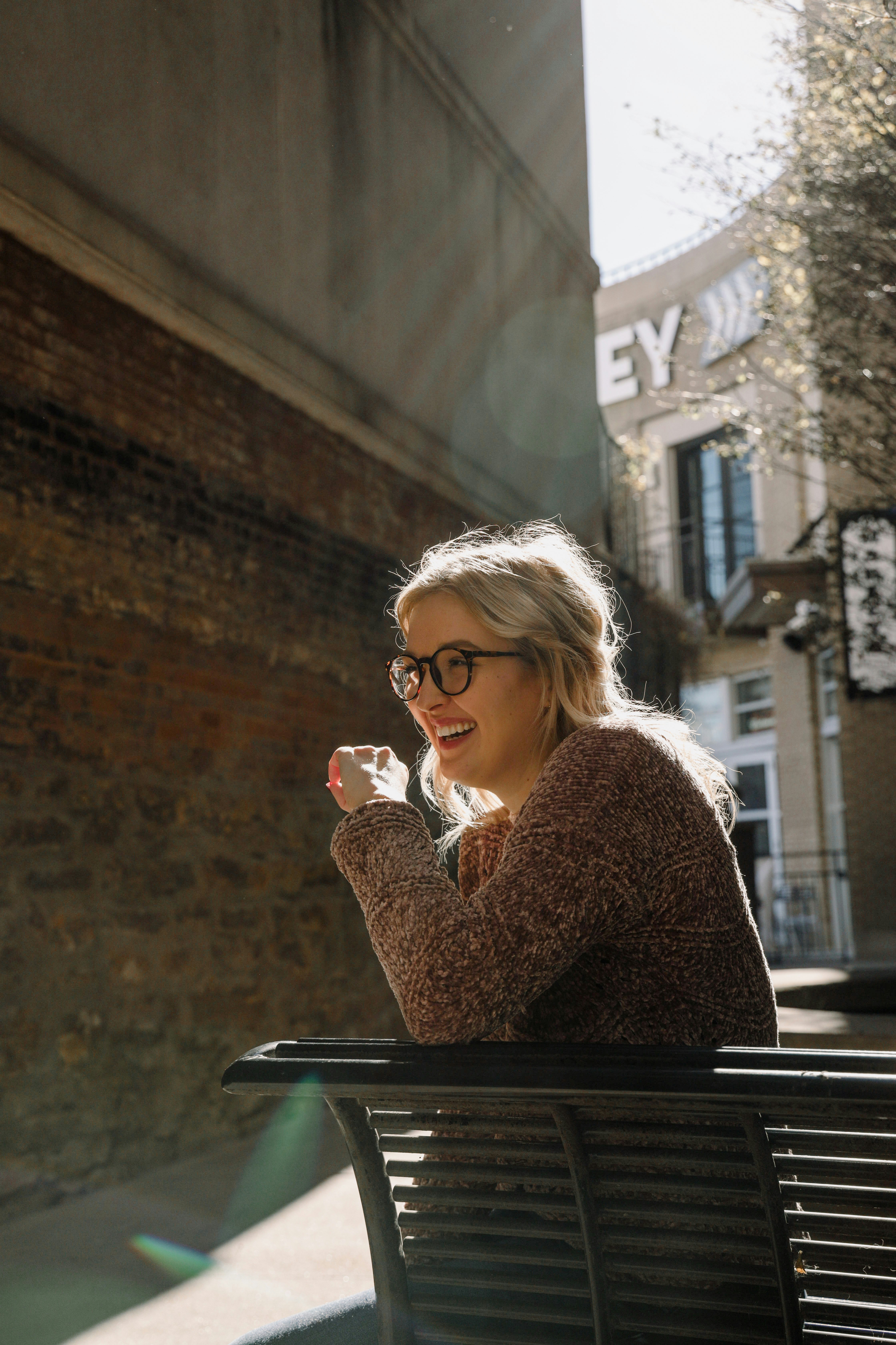 woman in brown sweater wearing eyeglasses sitting by the table